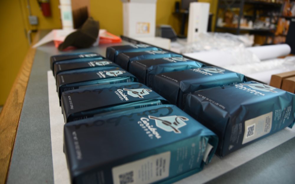 Partners + Hunt Homepage 1 Rows of Caribou Coffee packaging mockups featuring metallic teal bags, highlighting the precision and consistency in highly designed coffee packaging.